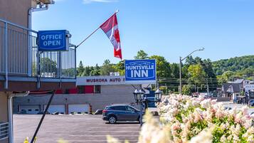 A parking lot with a car, a flag, and signs for 'HUNTSVILLE INN' and 'MUSKOKA AUTO'.