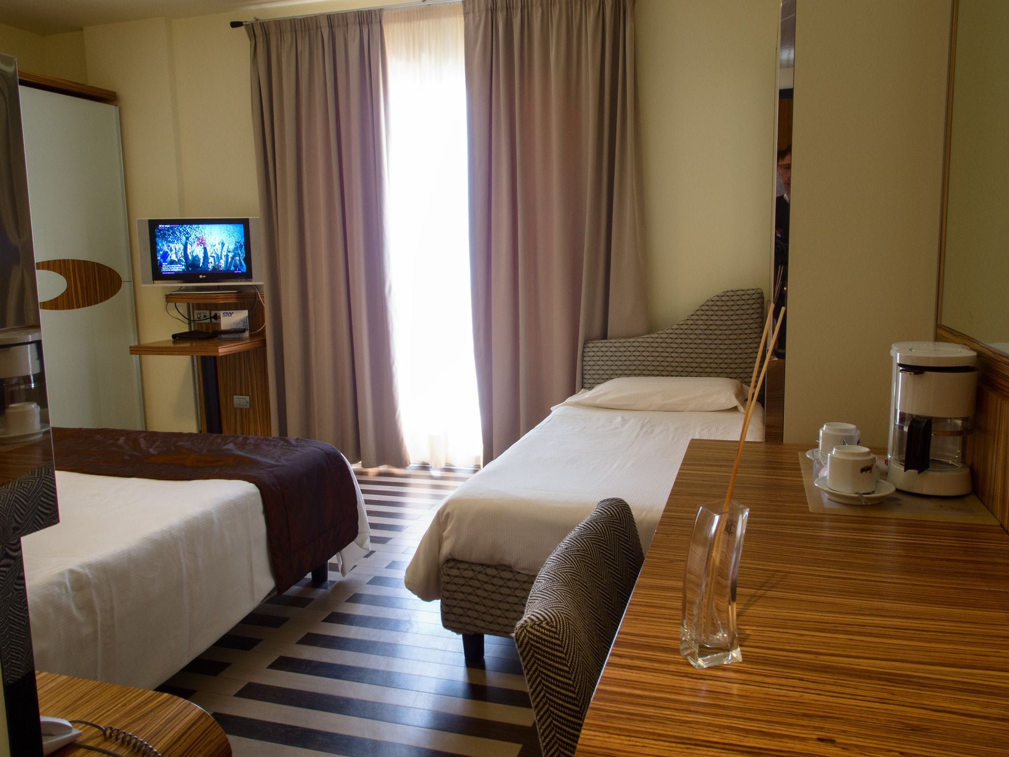 Ein Hotelzimmer mit zwei Betten, einem Fernseher, einer Kaffeemaschine und Blick ins Freie.