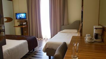 Ein Hotelzimmer mit zwei Betten, einem Fernseher, einer Kaffeemaschine und Blick ins Freie.