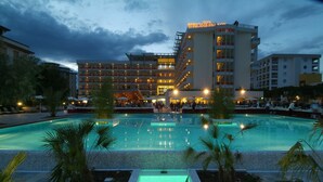 A hotel with a swimming pool, multiple floors, and outdoor seating areas.