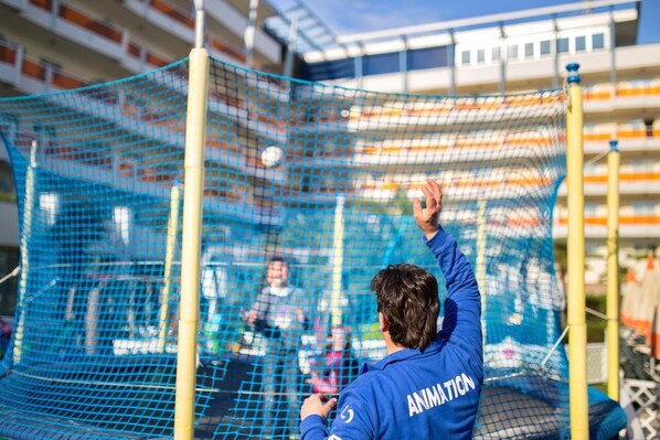 A netted enclosure with a person in a blue jacket labeled "ANIMATION" observing activities.