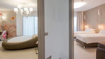 A modern hotel room with a round bean bag chair, a large bed, and a chandelier.