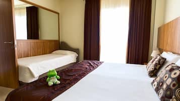 A hotel room with a large bed, a smaller bed, a mirror, and two windows with curtains.