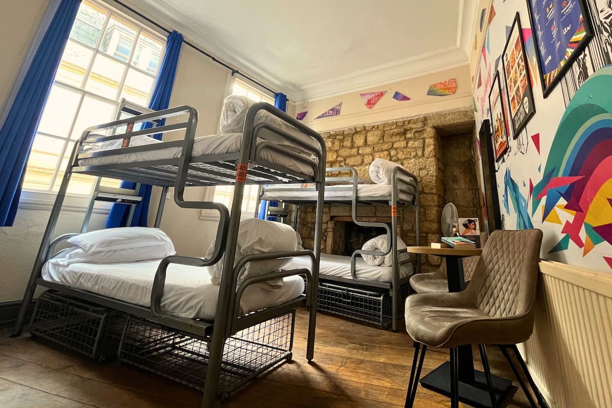 A bunk room with bunk beds, a chair, a small table, and a stone fireplace.