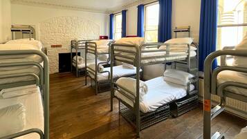 Une chambre d’hôtel avec des lits superposés, une cheminée et de grandes fenêtres ornées de rideaux bleus.
