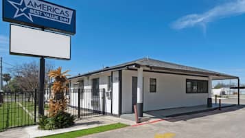 A small, single-story building with a white exterior and a black roof, labeled as the Americas Best Value Inn.