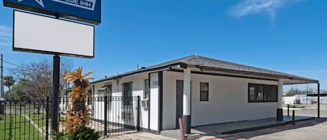 A small, single-story building with a white exterior and a black roof, labeled as the Americas Best Value Inn.