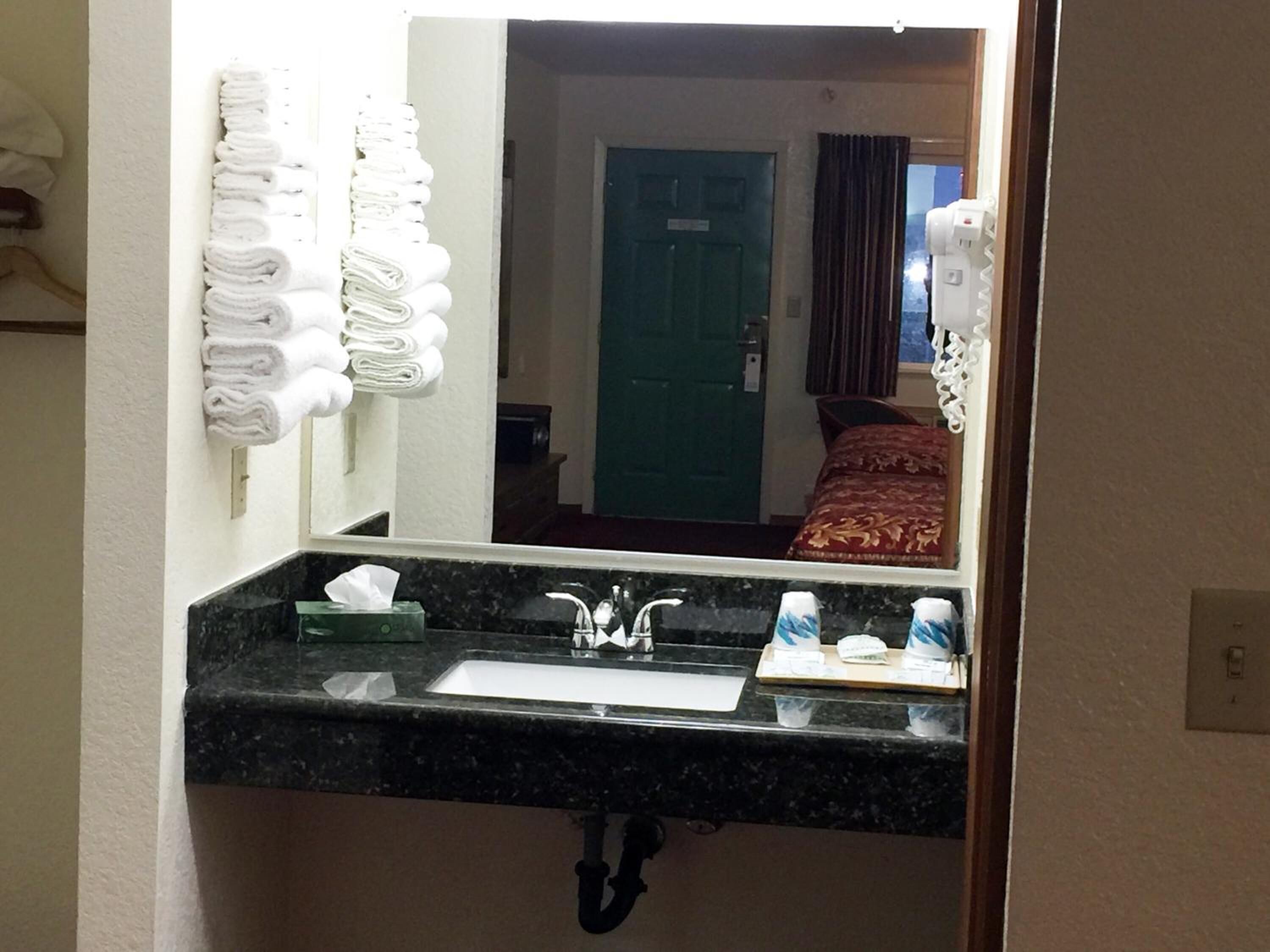 A hotel bathroom with a sink, mirror, and towel rack.