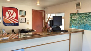 A reception desk with a computer, framed certificates, a map, and a wooden fish decoration. - Westward Inn (Brookings)