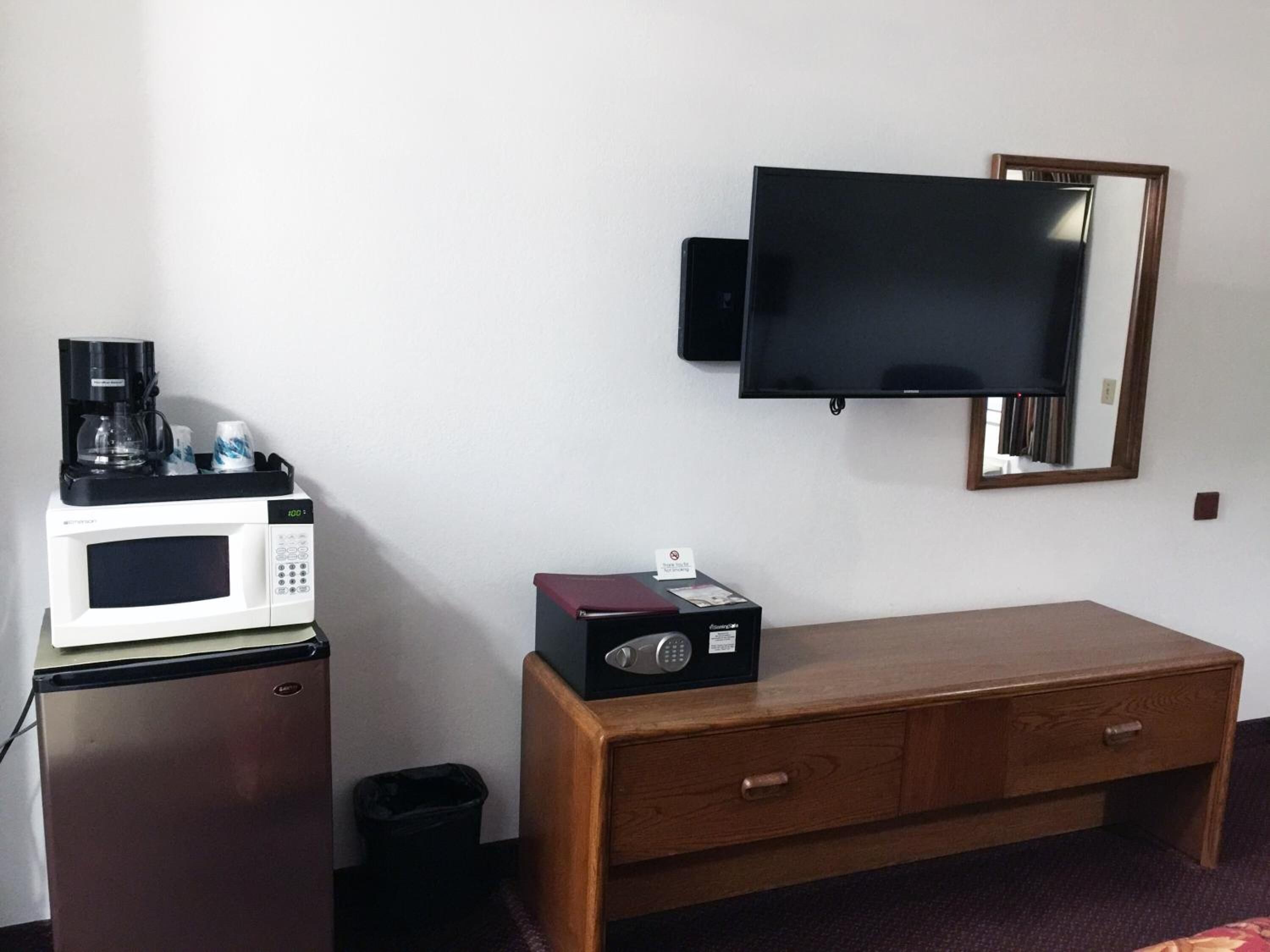 Habitación de hotel con microondas, cafetera y un mueble pequeño con un control remoto.