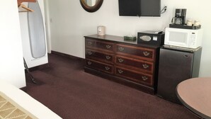 A hotel room with a dresser, a television, a microwave, and a coffee maker. - Westward Inn (Brookings)