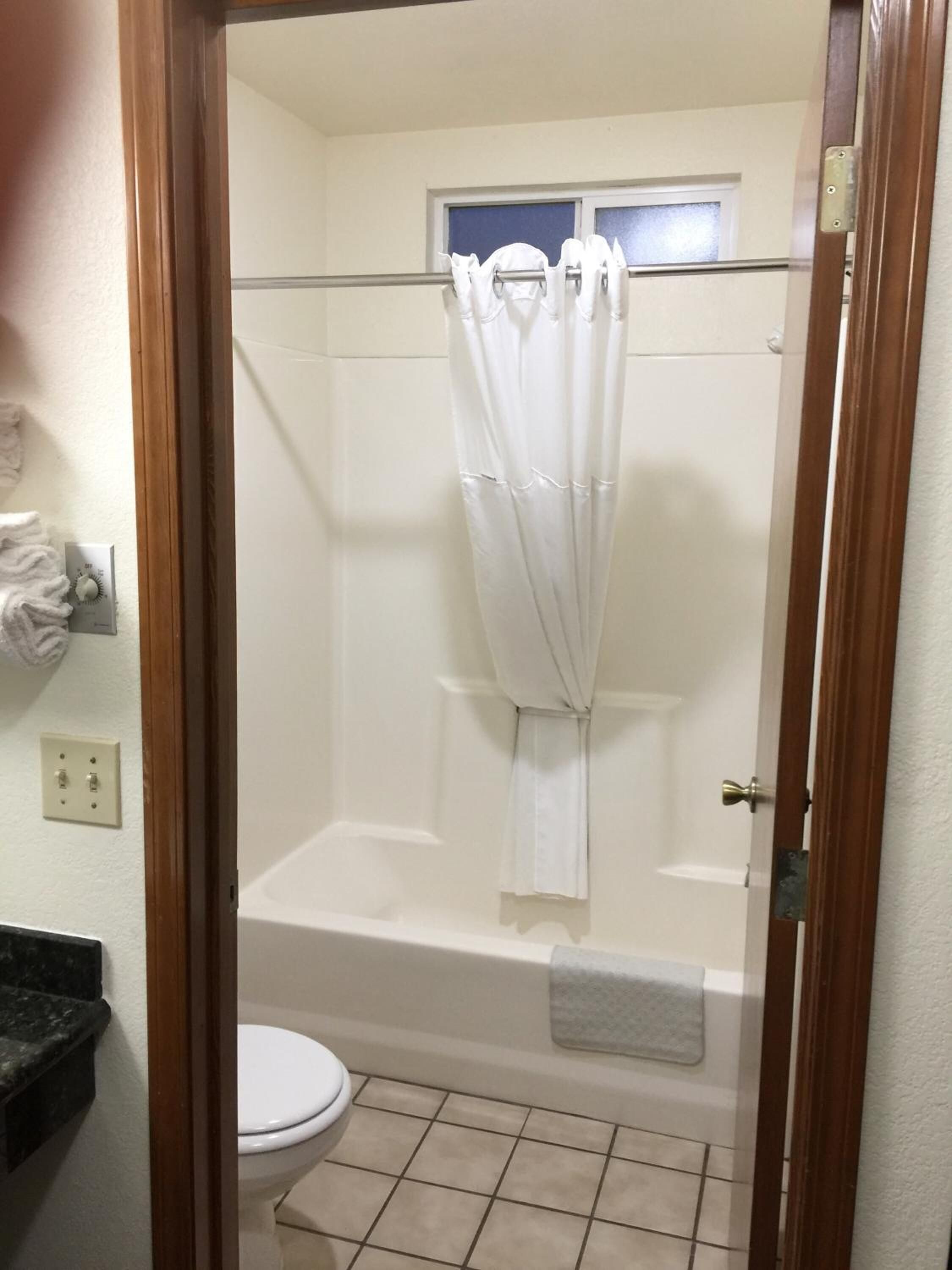 A bathroom with a bathtub, toilet, and a shower curtain.