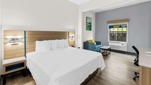 Ein modernes Hotelzimmer mit einem großen Bett, einem Schreibtisch, einem Sessel und einem Fenster mit Blick.