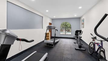 Una palestra con attrezzature per l'allenamento, tra cui tapis roulant, ellittica, cyclette e vogatore.