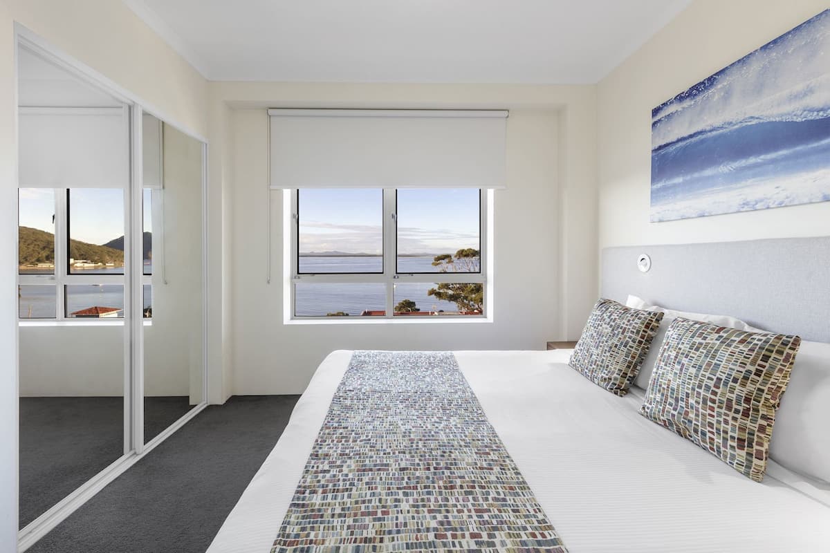 Ein Schlafzimmer mit einem großen Bett, Meerblick und einem Bild an der Wand.