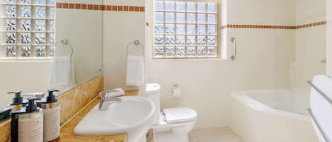 Un baño con lavamanos, inodoro, bañera y ventana con vidrio decorativo.