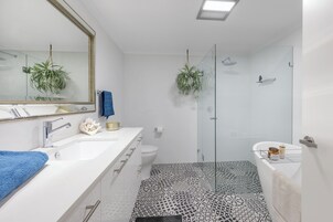Un baño moderno con un lavamanos blanco, un espejo grande y un box de ducha de vidrio.