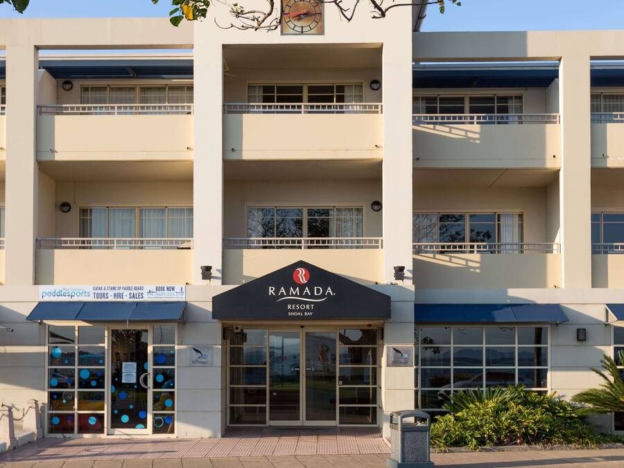 A multi-story building with a sign reading "RAMADA RESORT" and a sign for "paddle sports" below.