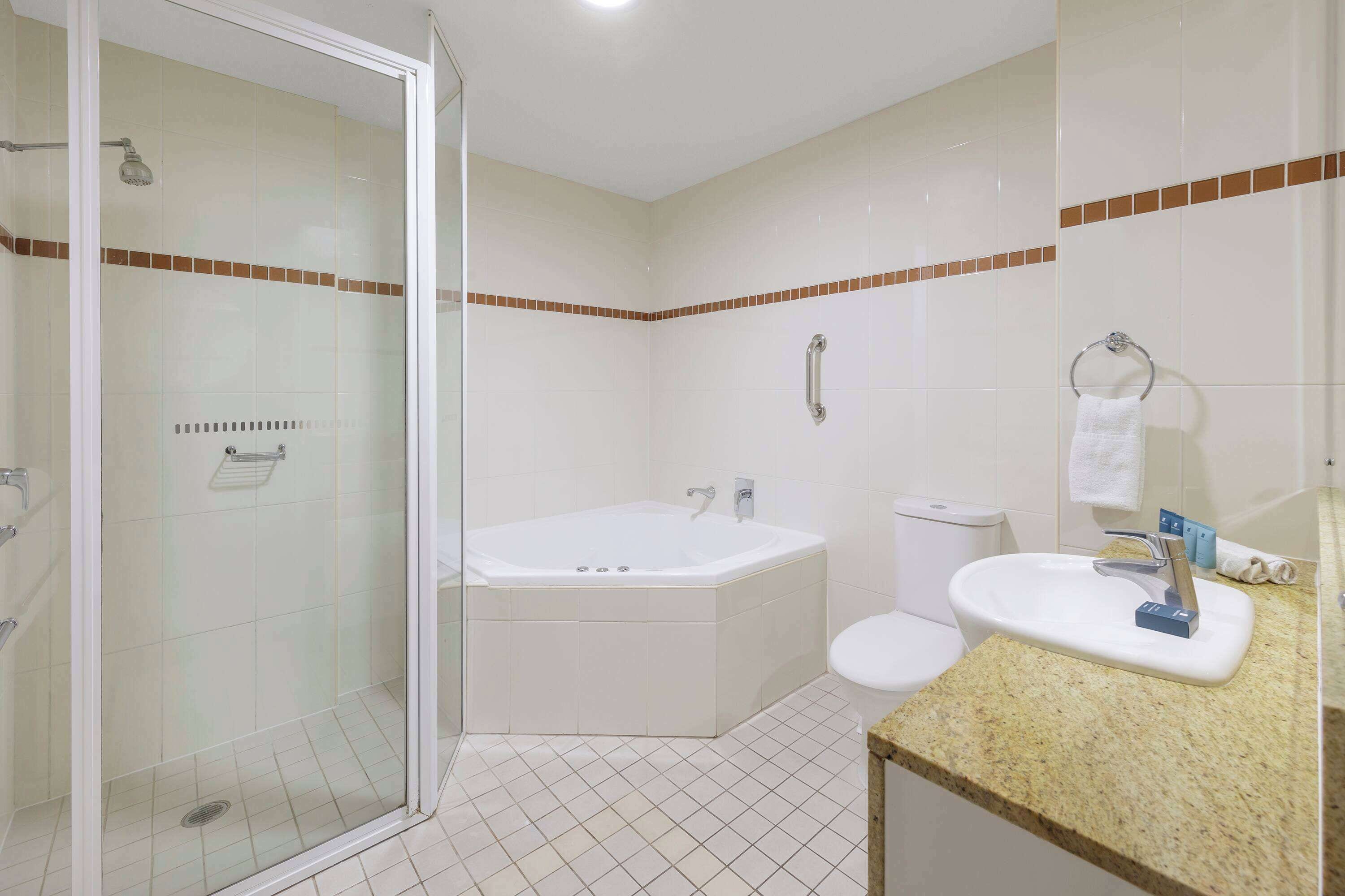 Une salle de bain avec une douche à parois de verre, une baignoire, des toilettes et un lavabo équipé d’un porte-serviettes.