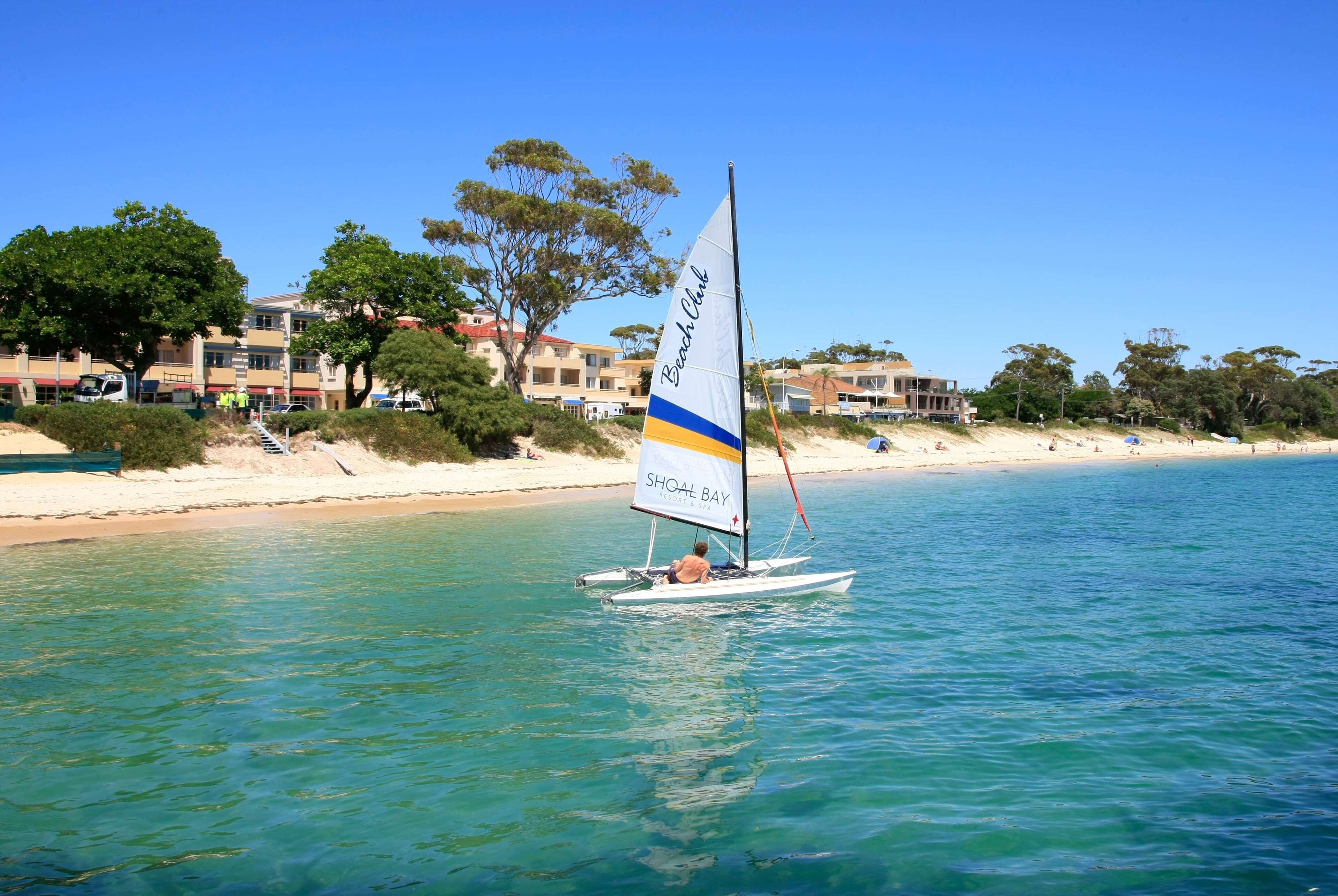 A sailboat with a 'Shoal Bay' sign on the water.