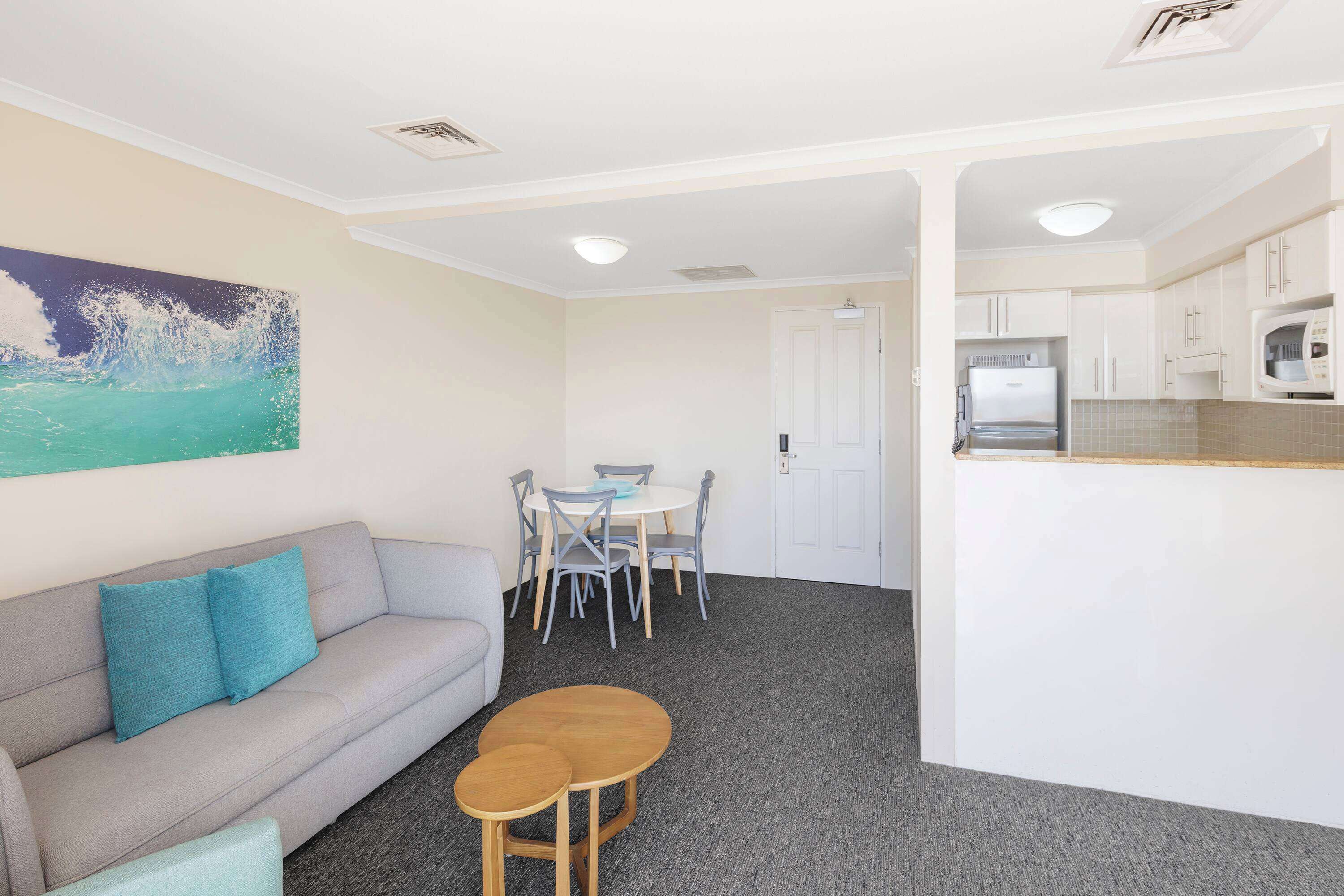 Un espacio habitable compacto con sofá, una pequeña mesa de comedor y una kitchenette.