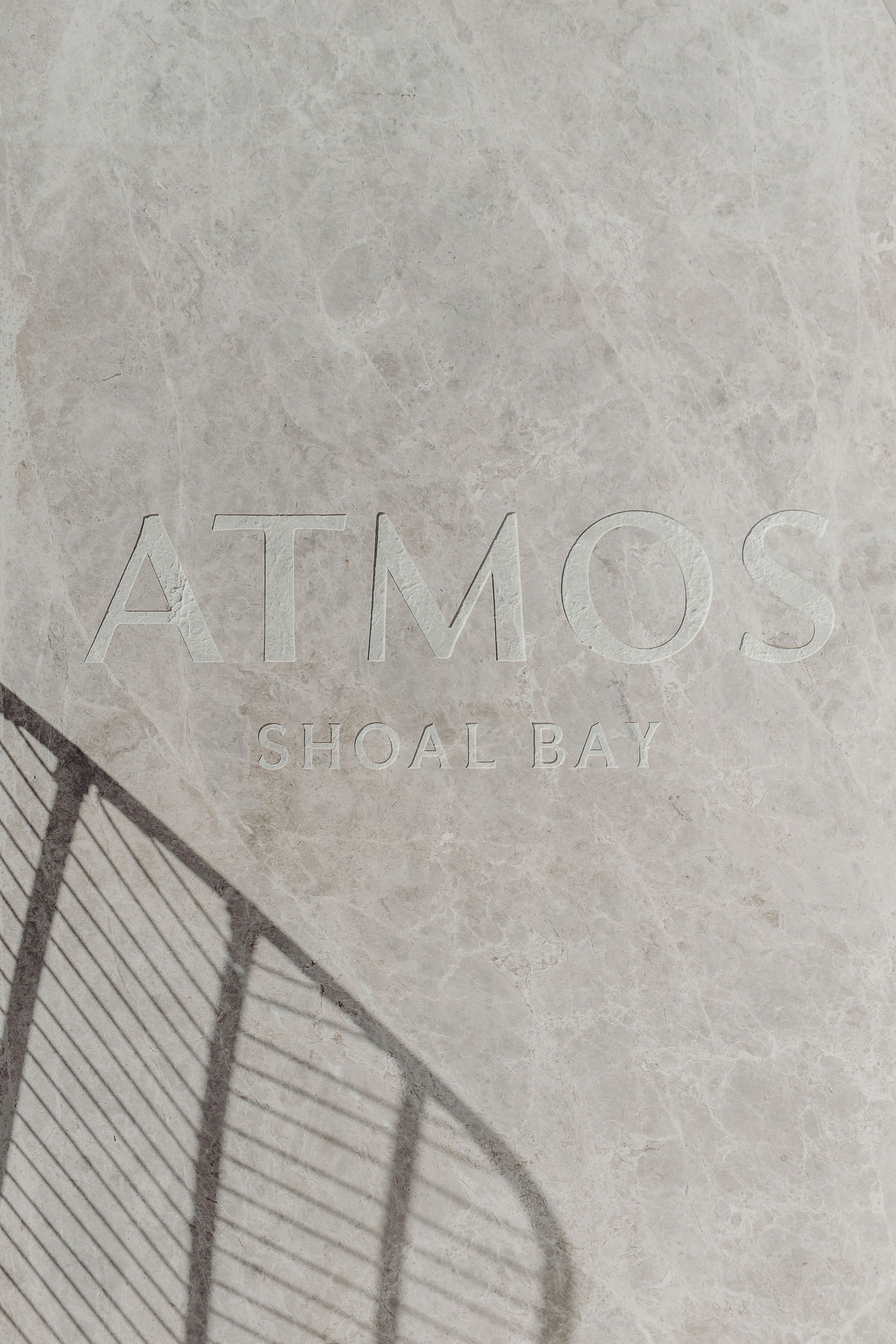 Eine strukturierte Steinwand mit dem erhabenen Text „ATMOS SHOAL BAY“.