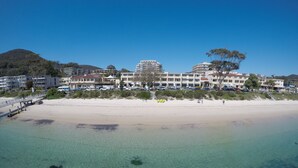 Een hotel aan het strand met meerdere gebouwen, een zandstrand en helder water.
