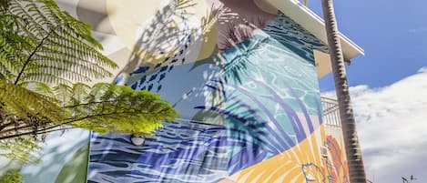 A staircase with a mural, palm trees, and greenery.