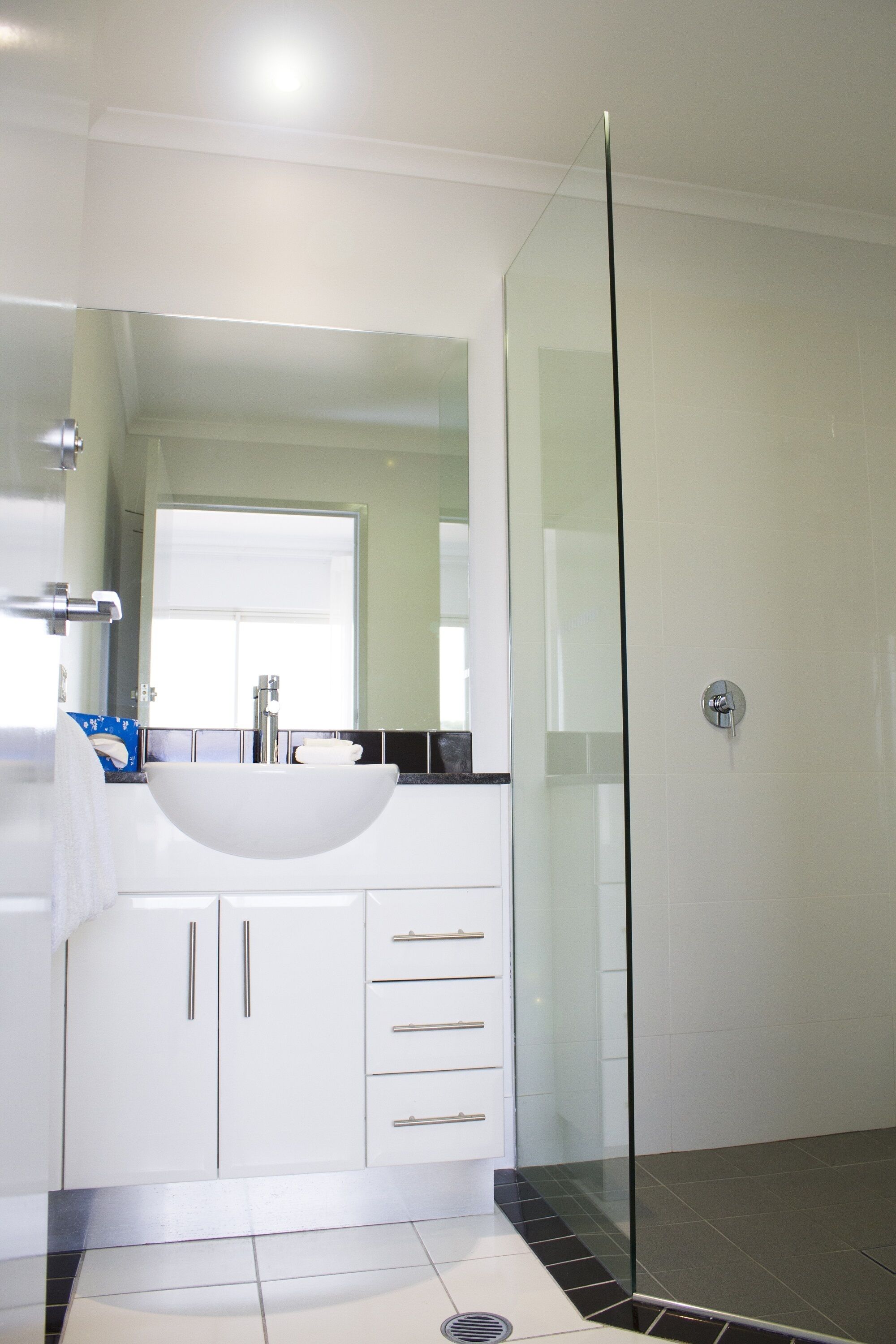A modern bathroom with a glass-enclosed shower, a white sink, and a mirror above it.