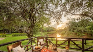 Une terrasse en bois offrant une vue sur une rivière, entourée d’une végétation luxuriante.