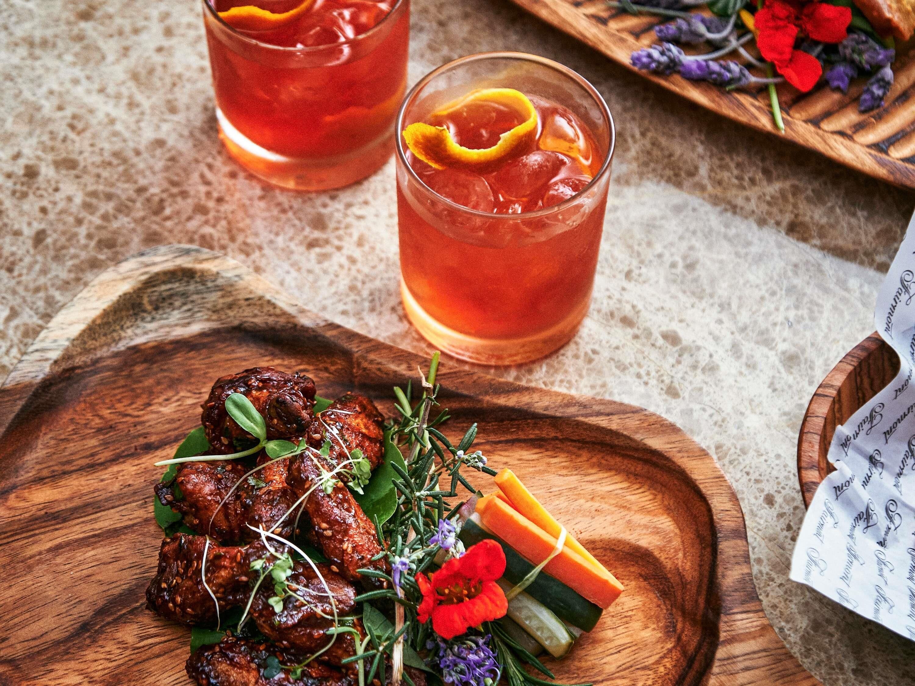 A wooden serving board with grilled meat, fresh herbs, and vegetables.