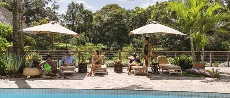 Una piscina al aire libre, sillones reclinables de piscina