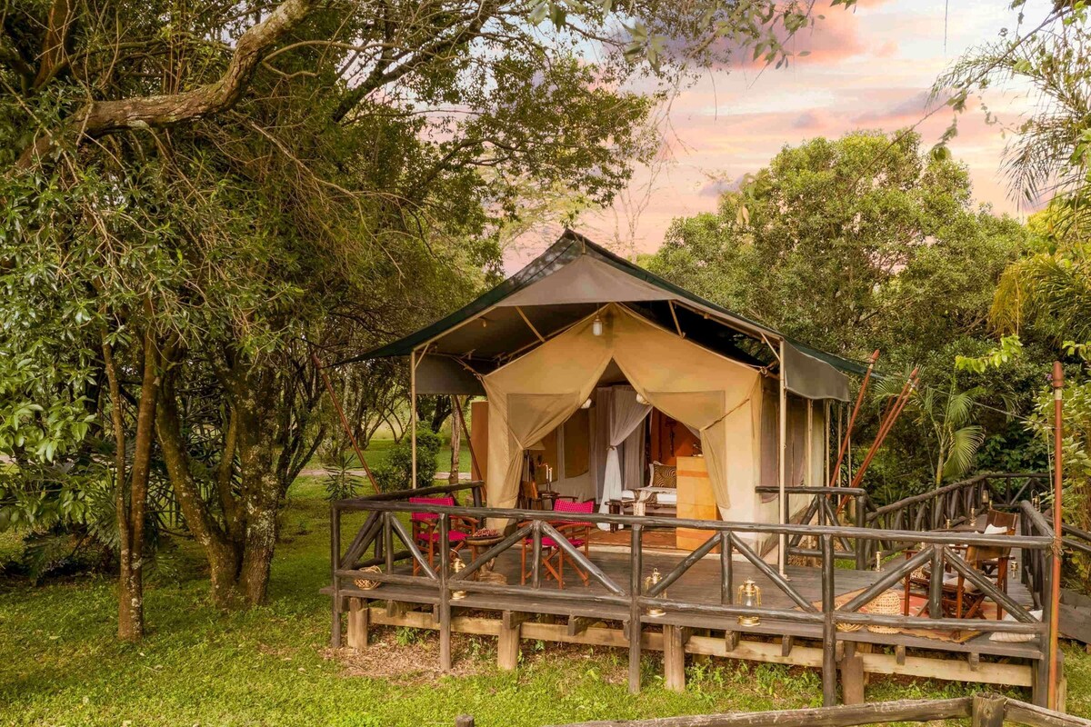 A rustic wooden structure with a covered porch, surrounded by lush greenery.