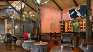 Een bar met houten meubels, ronde tafels en een drankenkast aan de muur.
