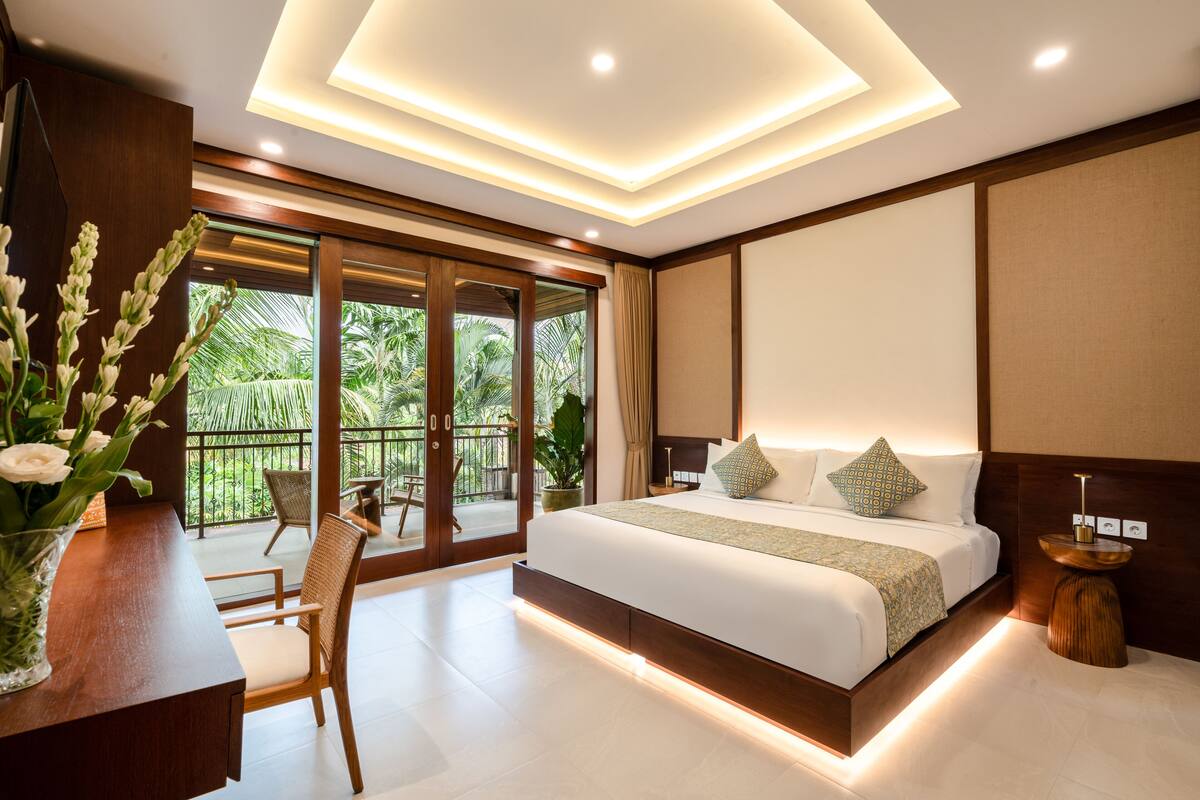 Ein modernes Schlafzimmer mit einem großen Bett, einem Holztisch und Blick ins Freie.