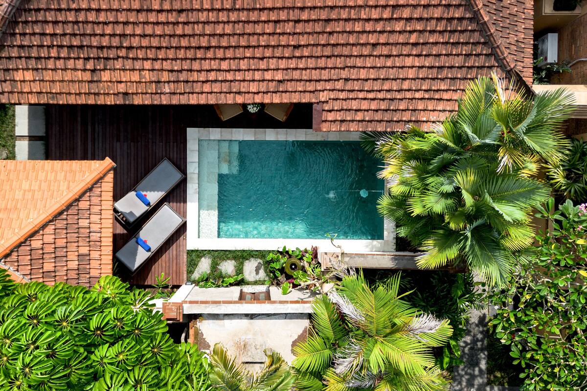 Eine Villa mit Pool, Ziegeldach und üppiger Bepflanzung.