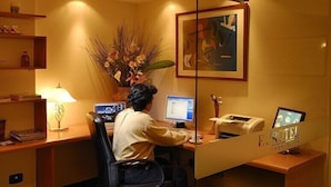 Un mostrador de recepción de hotel con una computadora, un teléfono y un florero.