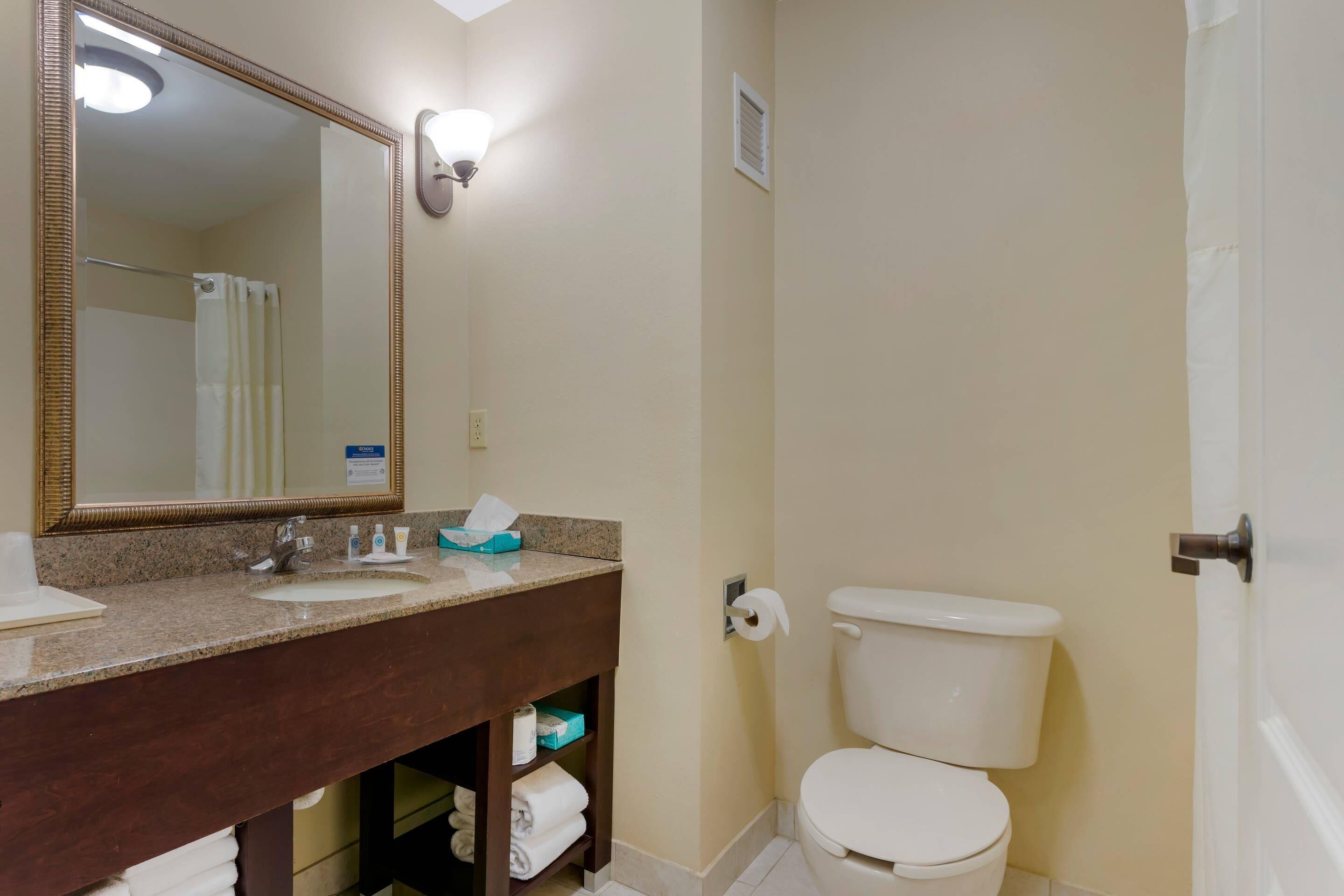 Un baño con lavamanos, espejo, inodoro y espacio para toallas.