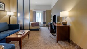 A hotel room with a sofa, a desk, a television, and a bed.