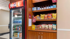 A vending machine stocked with various beverages and snacks, including Coca-Cola, water, and chips.