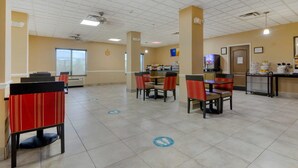 A spacious indoor area with multiple tables and chairs, a clock on the wall, and a vending machine.