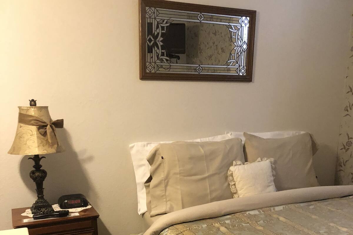 Une chambre à coucher avec un lit, une commode, une lampe et un miroir.