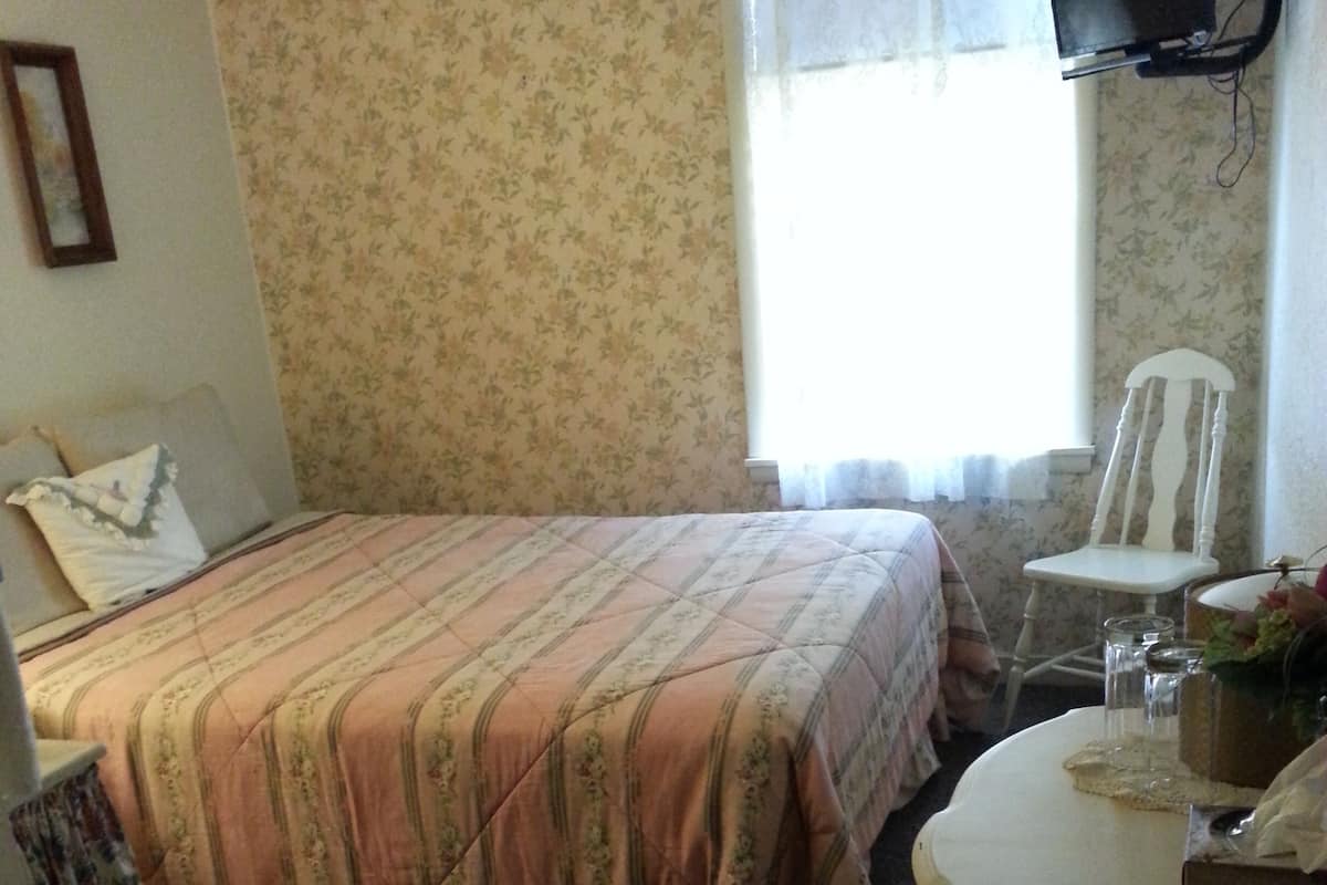 Une chambre à coucher avec un lit, une chaise, une table et un téléviseur.