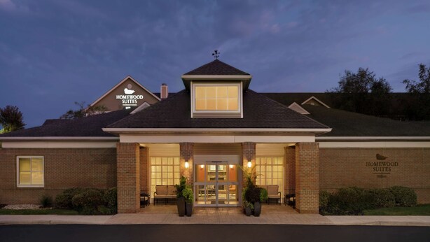 A hotel with a brick facade, a large entrance with a glass door, and a sign reading "Homewood Suites." - Homewood Suites by Hilton Allentown-Bethlehem Airport (Bethlehem)