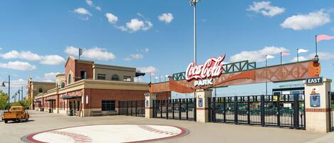 A Coca-Cola Park entrance with a brick building, a baseball diamond, and a vintage car.