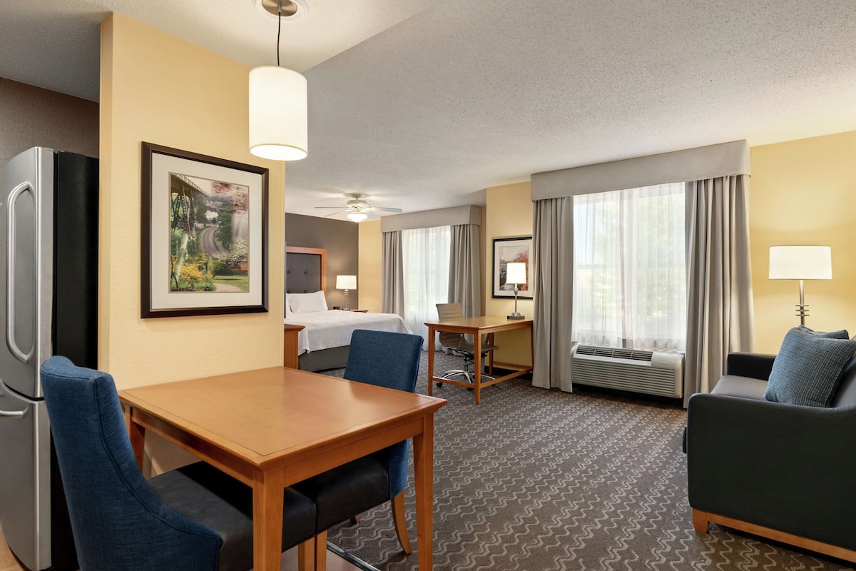 A hotel room with a bed, a desk, a dining table, and a sofa.