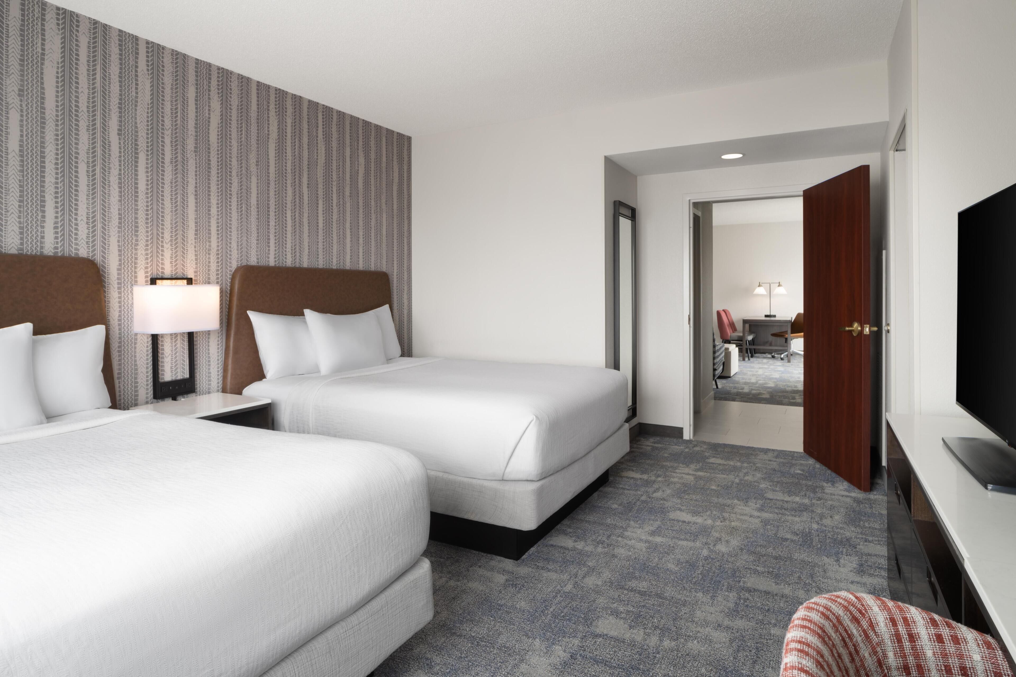 Une chambre d’hôtel avec deux lits, une télévision, un bureau et un miroir.