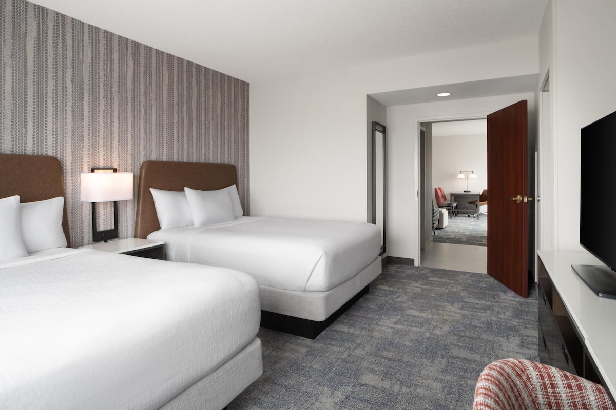 Une chambre d’hôtel avec deux lits, une télévision, un bureau et un miroir.