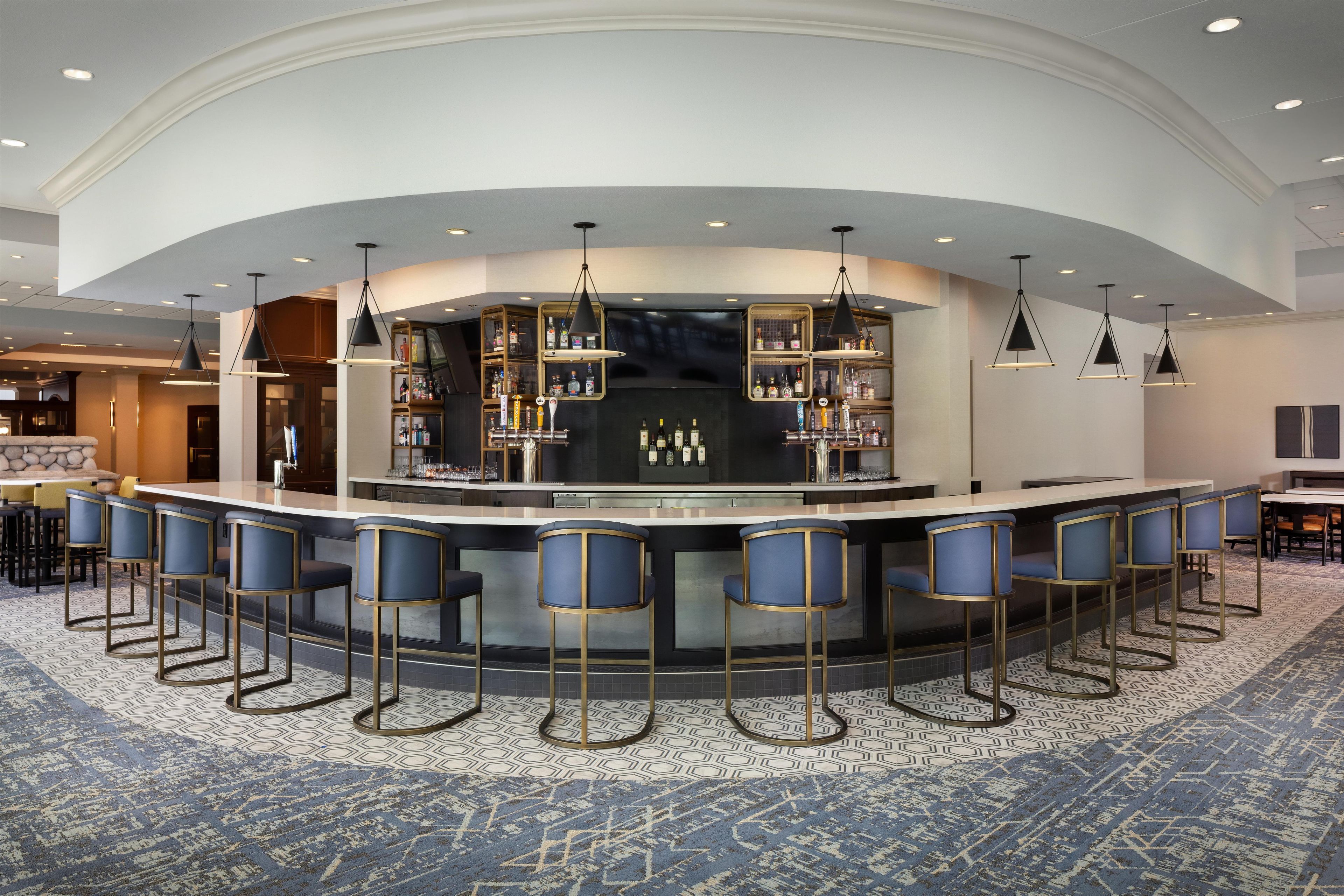 A bar area with a curved counter, multiple stools, and overhead lighting.