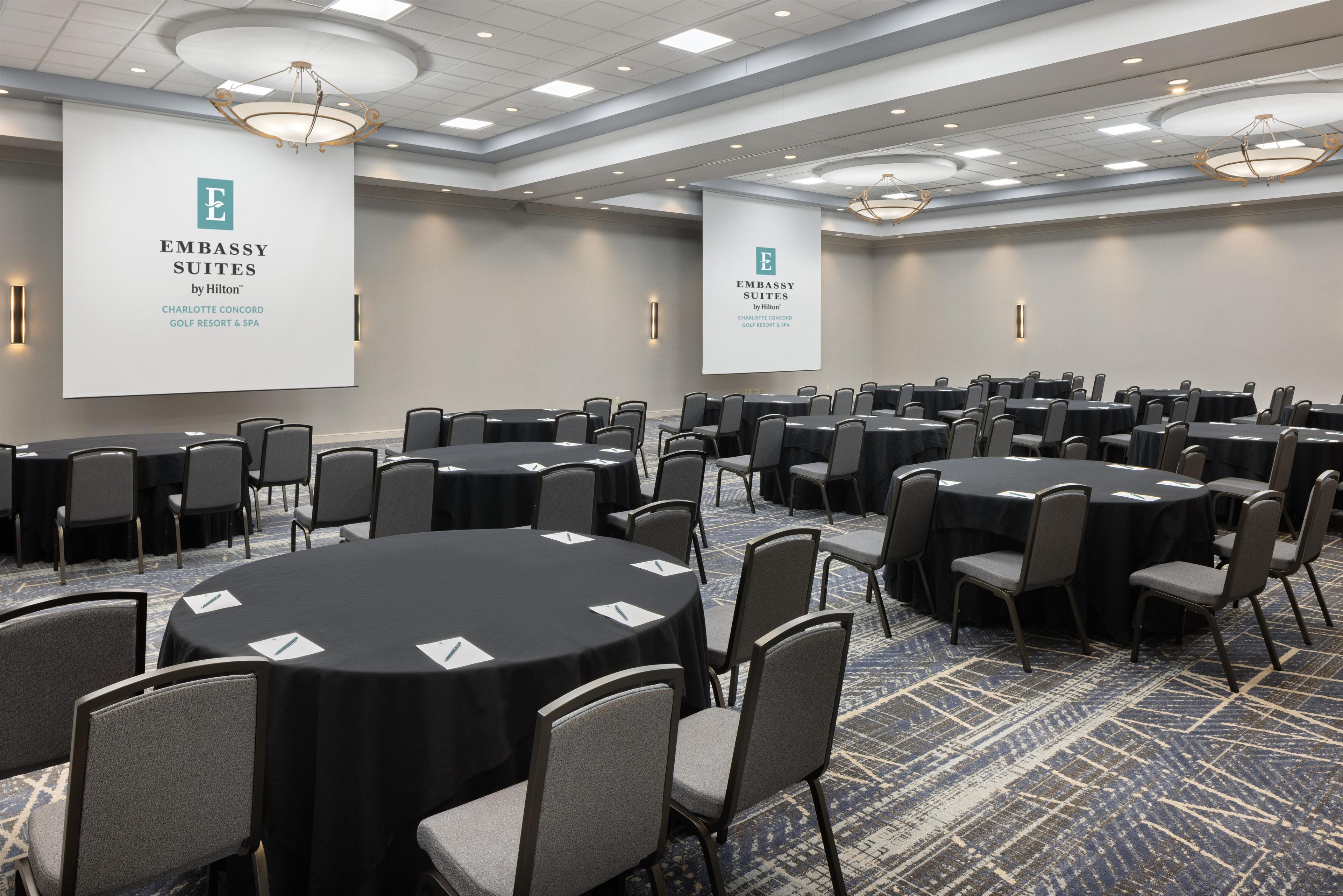 A conference room with round tables and chairs, large banners, and a patterned carpet.